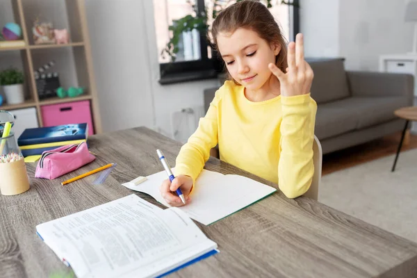 Estudiante chica con libro de escritura a cuaderno en casa —  Fotos de Stock