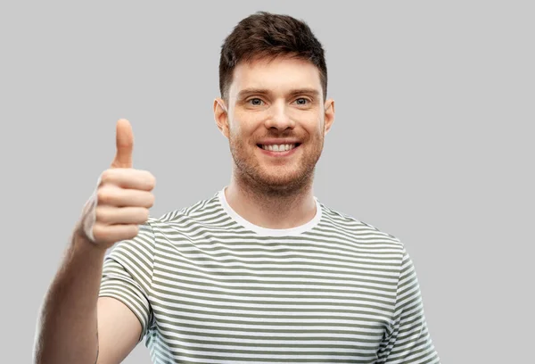 Sorridente giovane uomo mostrando pollici in su — Foto Stock