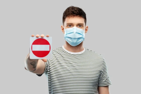 Junger Mann mit medizinischer Maske zeigt Stoppschild — Stockfoto