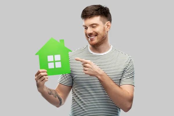 Усміхнений молодий чоловік тримає значок зеленого будинку — стокове фото