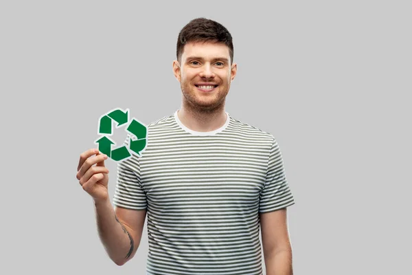 Усміхнений молодий чоловік тримає зелений знак переробки — стокове фото