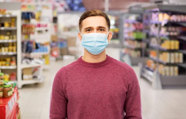 Молодой человек в медицинской маске в супермаркете — стоковое фото