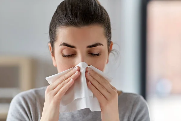 Nemocná žena foukání nos v papírové tkáni doma — Stock fotografie