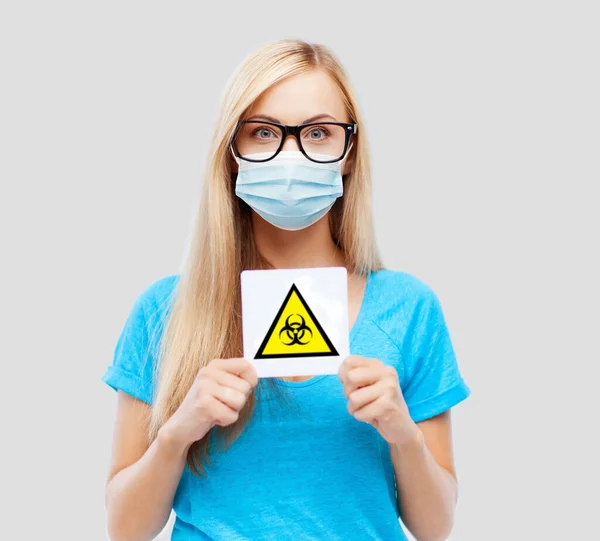 Женщина в медицинской маске с предупреждающим знаком boihazard — стоковое фото