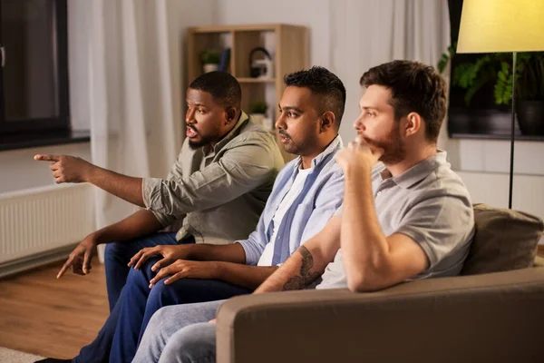 Amis masculins regarder la télévision et parler à la maison — Photo