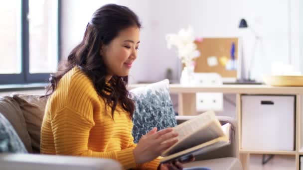 Mujer asiática lee libro y bebe agua en casa — Vídeos de Stock