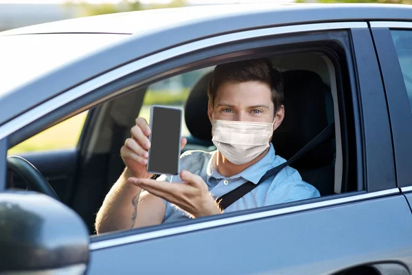 Male car driver with smartphone wearing face mask — Stock Photo, Image