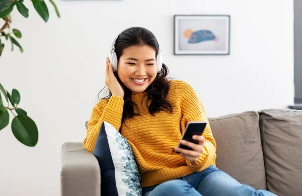 Mujer asiática con auriculares y smartphone en casa — Foto de Stock