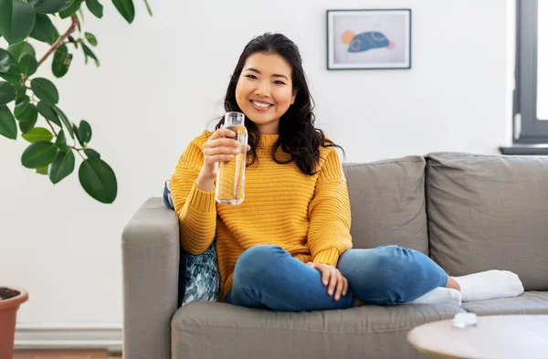Usmívající se asijské mladá žena pití vody doma — Stock fotografie