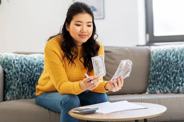 woman with money, papers and calculator at home