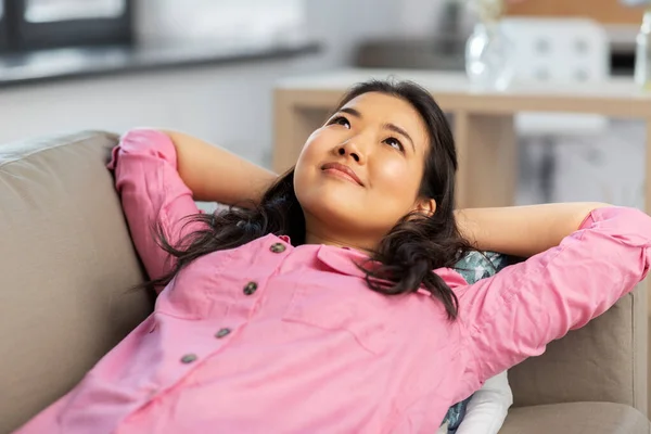 Азиатка лежит на диване и мечтает дома — стоковое фото