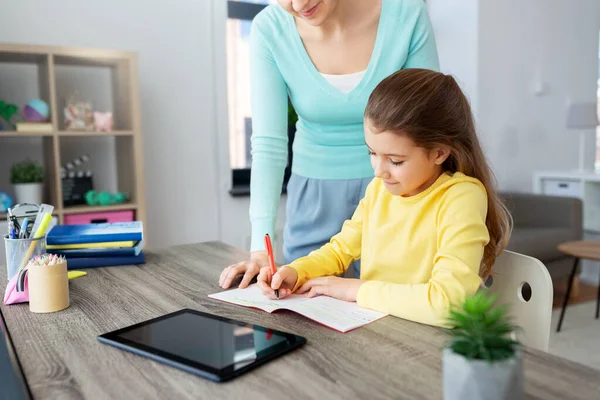 Mãe e filha com tablet pc fazendo lição de casa — Fotografia de Stock