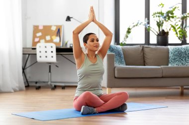 woman meditating in yoga lotus pose at home clipart