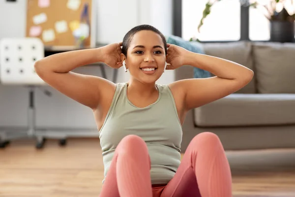 Mujer africana haciendo ejercicios abdominales en casa — Foto de Stock