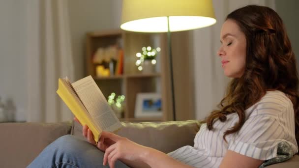 Szczęśliwa uśmiechnięta kobieta w ciąży czyta książkę w domu — Wideo stockowe