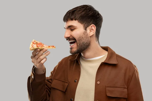 Glad leende ung man äter pizza — Stockfoto