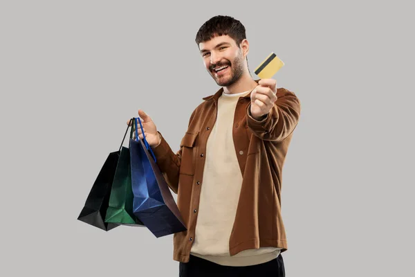 Щасливий молодий чоловік з сумками і кредитною карткою — стокове фото