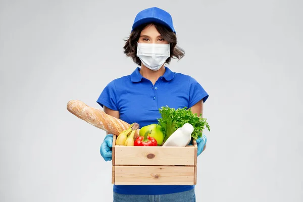 Levering vrouw in gezicht masker met voedsel in doos — Stockfoto