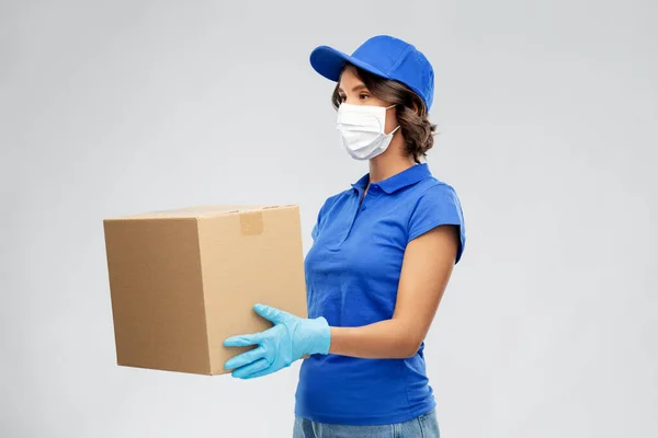 Delivery woman in face mask holding parcel box — Stock Photo, Image