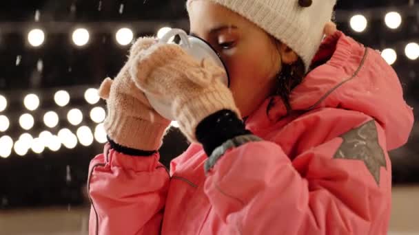 Κορίτσι πίνοντας ζεστό τσάι στο παγοδρόμιο το χειμώνα — Αρχείο Βίντεο