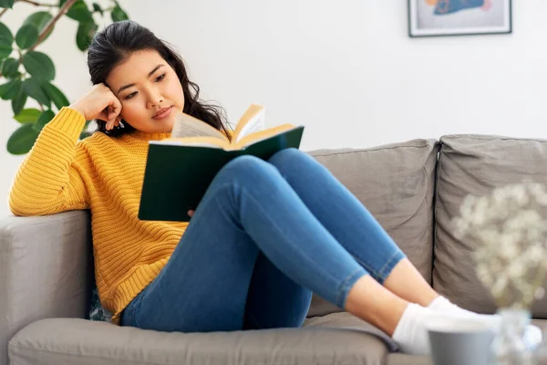 アジア系の若い女性が家で本を読んで — ストック写真