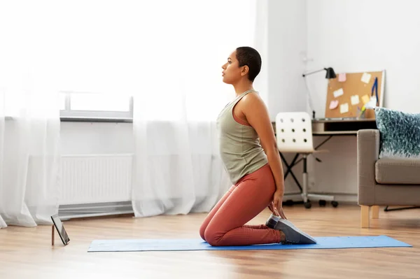 Mujer con tablet pc haciendo deporte o yoga en casa — Foto de Stock