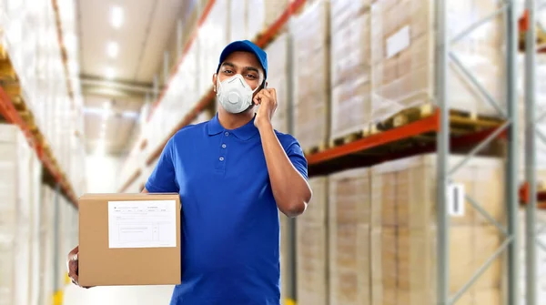 Delivery man in mask with smartphone and parcel — Stock Photo, Image