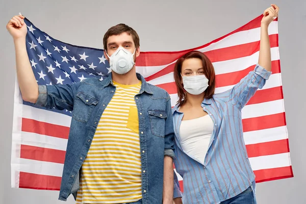 Pareja en la cara máscaras celebración de la bandera de América —  Fotos de Stock