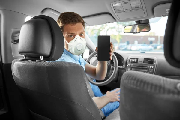 Motorista de carro masculino em máscara mostrando smartphone — Fotografia de Stock