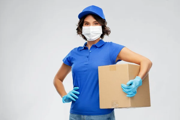 Entrega mulher no rosto máscara segurando caixa de parcela — Fotografia de Stock