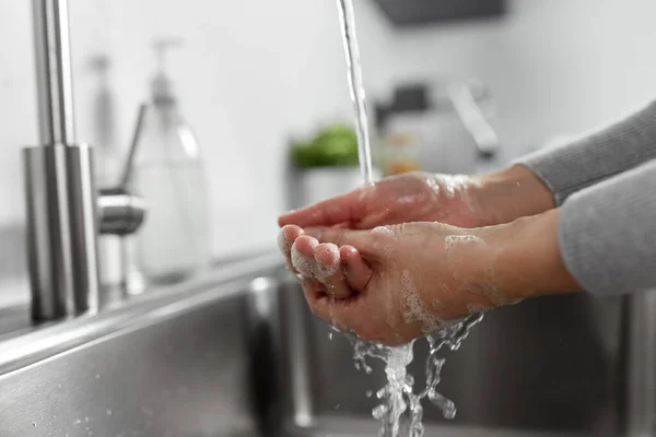 Vrouw wassen handen met vloeibare zeep in de keuken — Stockfoto