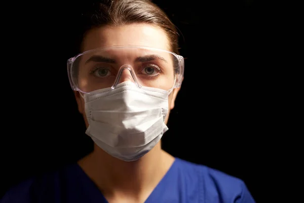 Female doctor or nurse in goggles and face mask — Stock Photo, Image