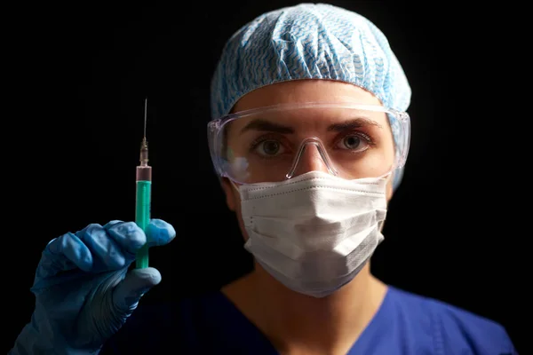Lékař s obličejovou maskou a brýlemi držící injekční stříkačku — Stock fotografie