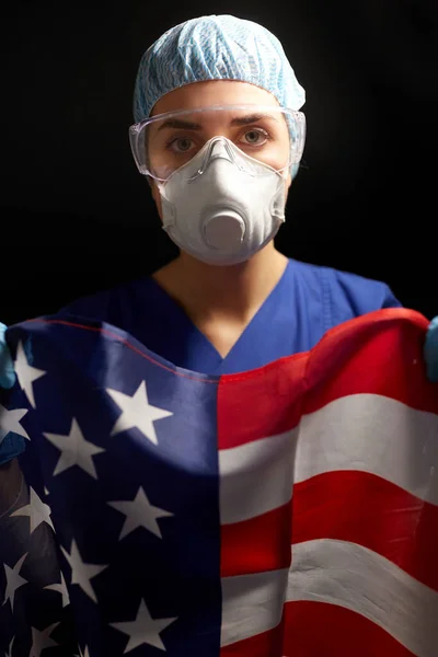 Doctor in goggles and mask holding flag of america — Stock Photo, Image