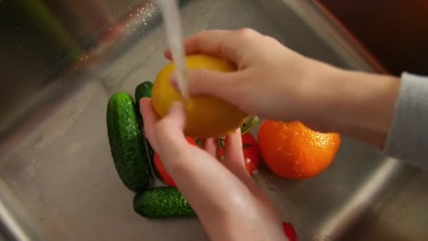 Vrouw wassen van groenten en fruit in de keuken — Stockvideo