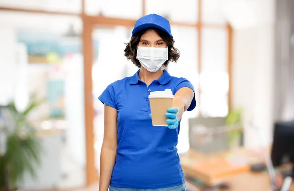 Vendedora em máscara facial com xícara de café no escritório — Fotografia de Stock