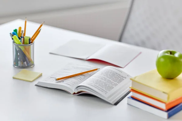 Bücher, Äpfel und Schulbedarf zu Hause auf dem Tisch — Stockfoto