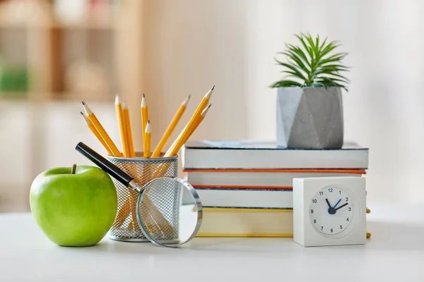 Libros, lupa, lápices, manzana en la mesa en casa — Foto de Stock