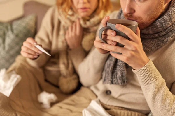 Close up of sick young couple drinking tea at home — Stock Photo, Image