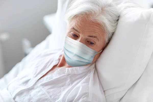 Maskeli yaşlı kadın hastanede yatakta yatıyor. — Stok fotoğraf