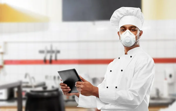 Koch in Atemschutzmaske mit Tablet-PC in der Küche — Stockfoto