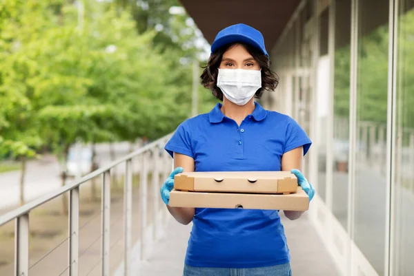 Femme de livraison en masque avec des boîtes à pizza à l'extérieur — Photo