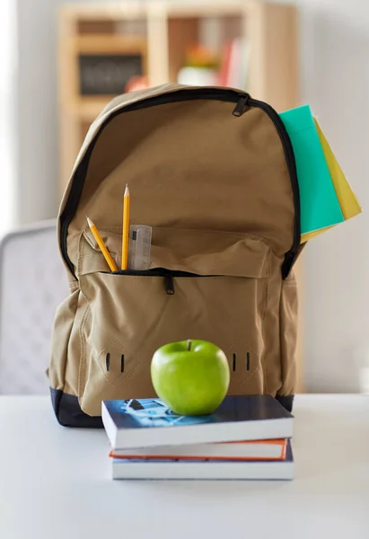Mochila escolar con libros y manzana en la mesa — Foto de Stock