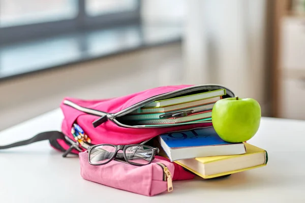 Hátizsák, alma és iskolai kellékek az asztalon — Stock Fotó