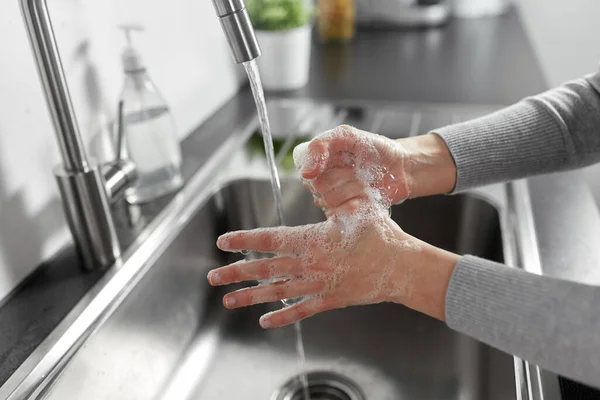 Femme se laver les mains avec du savon liquide dans la cuisine — Photo