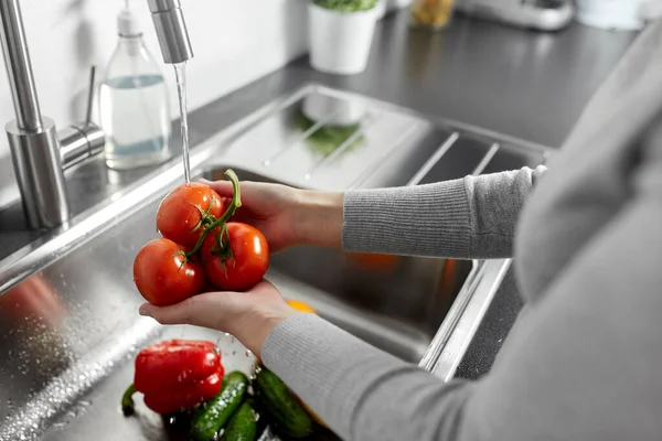Закрытие женщины, моющей овощи на кухне — стоковое фото