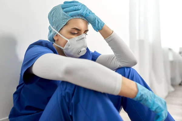 Sad doctor or nurse in face mask holding to head — Stock Photo, Image