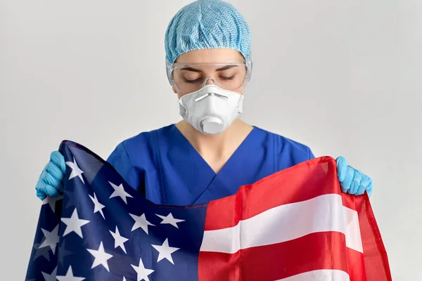 Läkare i glasögon och mask håller flagga av Amerika — Stockfoto