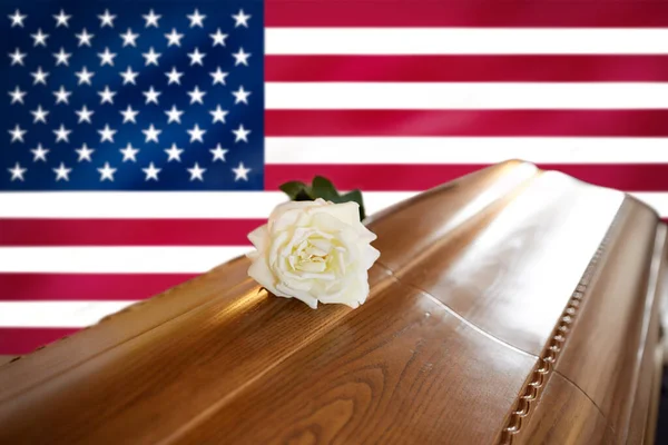 Rosa bianca su bara di legno sopra bandiera d'America Foto Stock