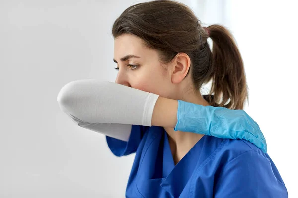 Γιατρός ή νοσοκόμα βήχα που καλύπτει το στόμα με αγκώνα Φωτογραφία Αρχείου